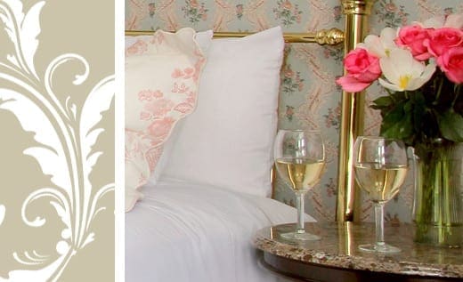 Victorian Village Suite room detail bed and side table with flowers and wine glasses